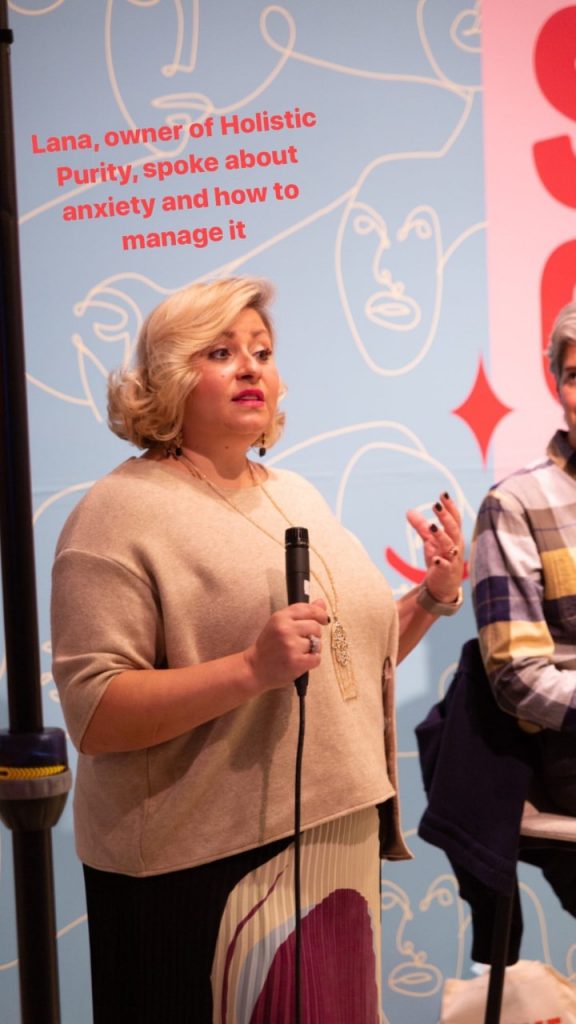 Woman speaking into a microphone at an indoor event.